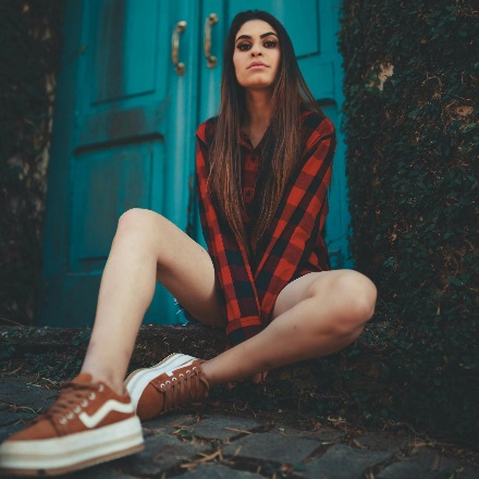 Photo of Woman in Red Plaid Shirt Sitting on the Ground In Front of Blue Door