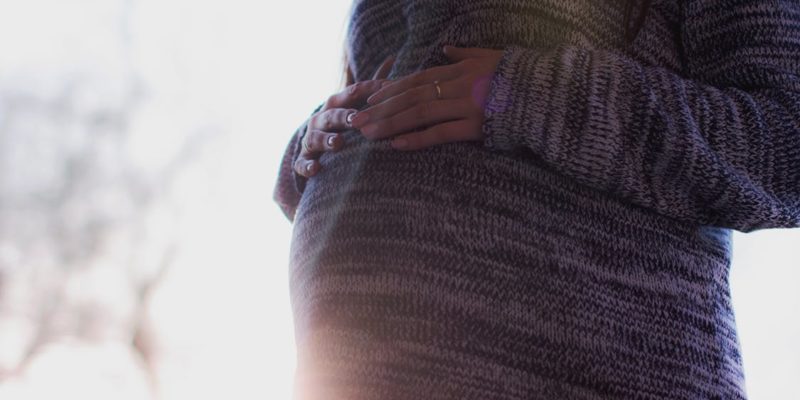 Pregnant Woman Wearing Marled Gray Sweater Touching Her Stomach